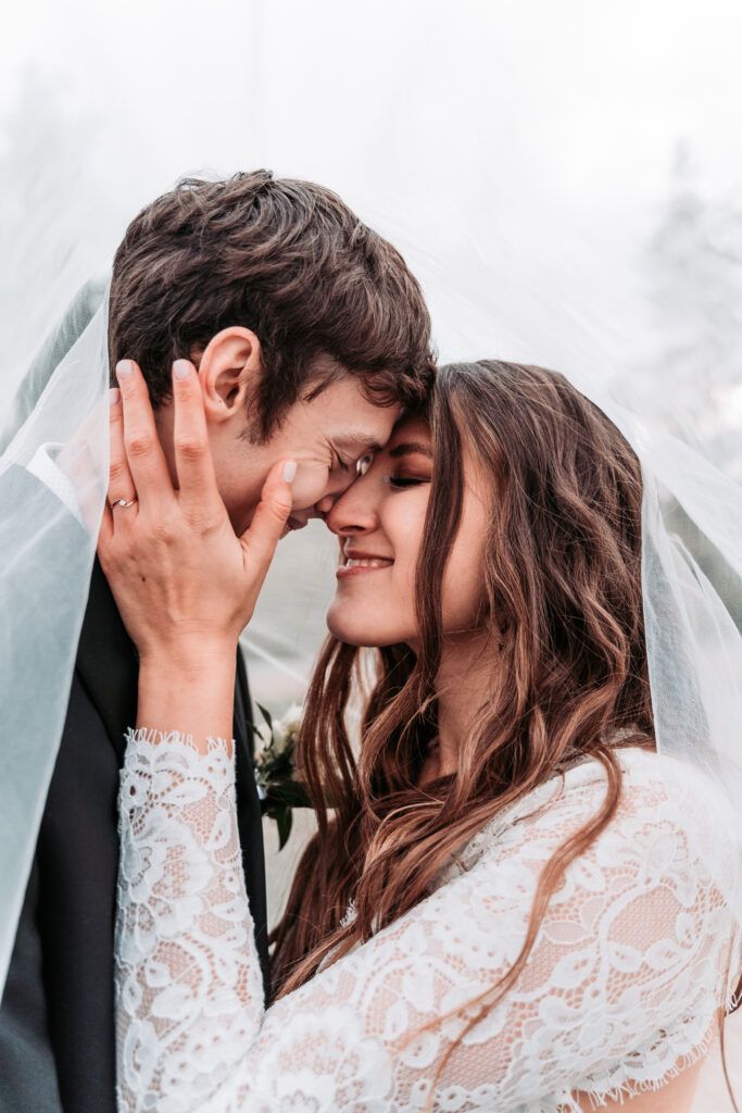primer-plano-de-una-pareja-de-recien-casados-con-los-ojos-cerrados-haciendo-el-romance-bajo-el-velo