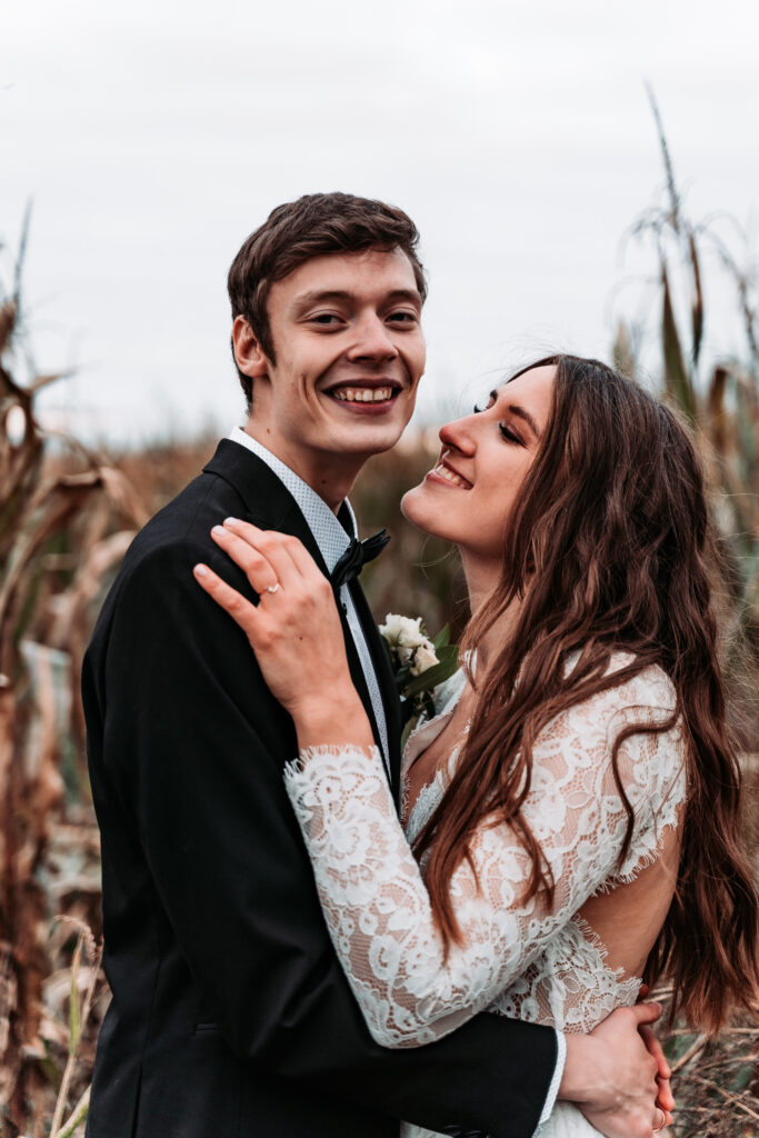 una-pareja-de-recien-casados-sonrientes-abrazandose-mientras-estan-de-pie-contra-el-cielo
